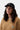 Casquette Carhartt WIP Madison Logo noire portée par une femme aux cheveux bouclés et un pull en maille camel.