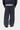 Pantalon de survêtement Bolon Carhartt WIP gris foncé coupe large, porté par derrière avec une veste et une chemise rayée.