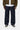 Pantalon Aaron Carhartt WIP bleu foncé, coupe ample, porté avec une chemise blanche, une veste kaki et des baskets noires.