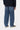 Pantalon Aaron Carhartt WIP bleu, coupe large, porté de dos par un homme avec un pull foncé et des baskets. Tenue casual.