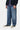 Pantalon Aaron Carhartt WIP pour homme, jean bleu coupe large porté avec un pull zippé et des baskets noires.