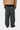 Vue arrière d'un homme portant le pantalon Single Knee Carhartt WIP vert foncé avec une veste beige, montrant les poches et le logo.