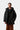 Homme portant le parka Carhartt WIP Stanwood noir avec capuche, t-shirt foncé et pantalon côtelé marron.