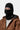 Portrait d'une personne portant un masque Blevin noir Carhartt WIP, une veste marron et un pull blanc. Seuls les yeux sont visibles.