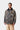 Homme portant le manteau Lander Coat Carhartt WIP camouflage avec col en velours côtelé, sur chemise grise et pantalon kaki.