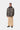 Homme portant le manteau Lander Carhartt WIP imprimé camouflage, avec col foncé, pantalon beige et mocassins noirs.