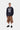 Mannequin homme portant le sweat Carhartt WIP 1989 Winners Dark Navy, un short utilitaire marron et des chaussures noires.
