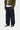 Pantalon Aaron Carhartt WIP en denim foncé à coupe large, porté avec un blouson kaki et des baskets.