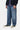 Pantalon Aaron Carhartt WIP pour homme, jean bleu coupe large porté avec un pull zippé et des baskets noires.
