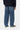 Pantalon Aaron Carhartt WIP bleu, coupe large, porté de dos par un homme avec un pull foncé et des baskets. Tenue casual.