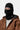 Portrait d'une personne portant un masque Blevin noir Carhartt WIP, une veste marron et un pull blanc. Seuls les yeux sont visibles.