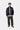 Veste Bolon Dark Navy de Carhartt WIP, modèle homme, portée avec une chemise à rayures, un pantalon large et des mules en daim.
