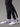Chaussettes Running SAIMAA AYAQ blanches et grises portées avec un pantalon de course noir. Gros plan sur les pieds et chevilles.
