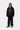 Homme portant un Manteau Lander Carhartt WIP noir, un hoodie marron, un pantalon noir et des chaussures beiges.
