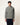 Homme portant un hoodie Homecore Terry gris-vert texturé avec cordon à embouts rouges et un pantalon bleu foncé.
