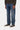 Pantalon Klondike Carhartt WIP bleu foncé délavé, porté par un homme avec un pull marron et des baskets.