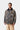 Homme portant le manteau Lander Coat Carhartt WIP camouflage avec col en velours côtelé, sur chemise grise et pantalon kaki.