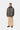 Homme portant le manteau Lander Carhartt WIP imprimé camouflage, avec col foncé, pantalon beige et mocassins noirs.