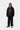 Homme portant un Manteau Lander Carhartt WIP noir, un hoodie marron, un pantalon noir et des chaussures beiges.