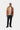 Homme portant le pantalon Carhartt WIP Newel Blue One Wash, un jean bleu foncé, avec une veste marron et un t-shirt blanc.