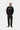 Pantalon Newel Carhartt WIP noir porté par un homme avec un sweat-shirt noir et des chaussures marron.