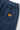 Close-up of Service Works Pinstripe Denim Chef Pants, showing the back pocket with an orange logo and elastic waistband.