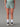 Short Trail LEVICO AYAQ femme vert sauge avec des inserts noirs, porté avec des chaussettes blanches et des chaussures de trail.