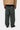 Vue arrière d'un homme portant le pantalon Single Knee Carhartt WIP vert foncé avec une veste beige, montrant les poches et le logo.