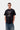 Homme portant un T-shirt noir Carhartt WIP S/S Restraint avec imprimé graphique d'arbre, fruit et texte, et un jean bleu.