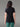 Femme de dos portant le T-shirt 100% Mérinos BIAFO AYAQ noir à manches courtes, avec un pantalon vert.