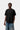 Modèle homme portant un T-shirt Small Heart noir Carhartt WIP avec logo cœur, un jean bleu et un collier argenté.