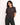 Femme souriante portant un t-shirt OLOW Taijitu noir avec un motif bleu sur la poitrine, et un pantalon vert foncé.